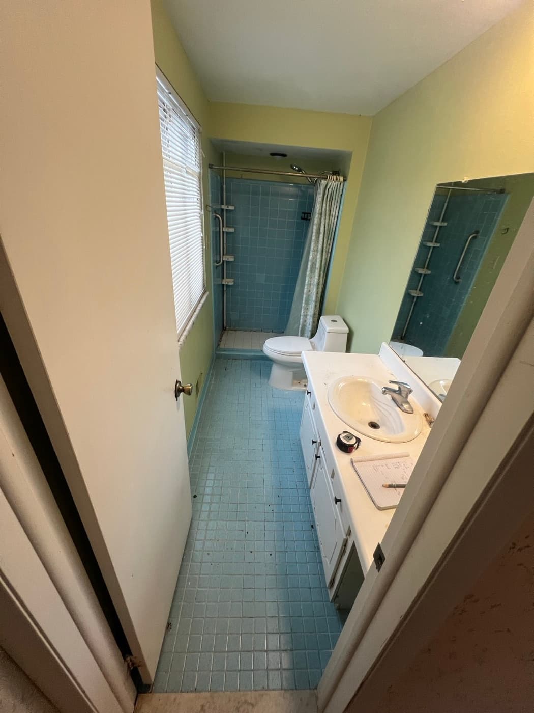 The same bathroom before the remodel, with dated blue tile and worn fixtures