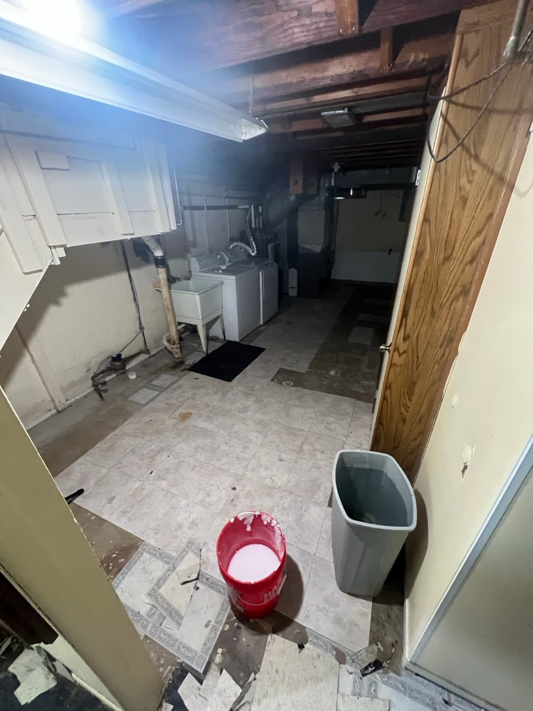 Basement before renovation with cracked, peeling tile flooring